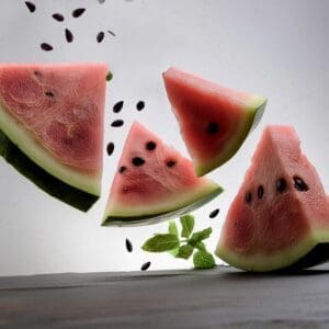 Flying pieces of fresh watermelon with mint and seeds isolated on white background
